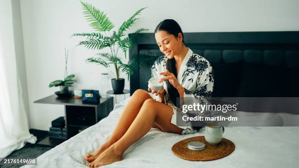 woman at home using shea butter body cream - creme corporal imagens e fotografias de stock
