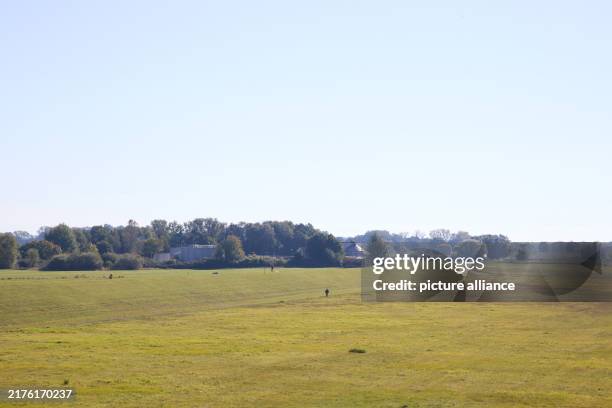 October 2024, Schleswig-Holstein, Lauenburg: A cloudless sky over a dyke and green meadows. Photo: Georg Wendt/dpa