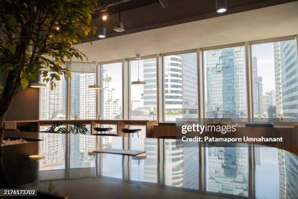 der moderne coworking space befindet sich in einem belebten geschäftsviertel, das von hohen gebäuden umgeben ist, und verfügt über stilvolle möbel, ein offenes design und viel tageslicht. ideal für zusammenarbeit und kreativität. - open space office stock-fotos und bilder