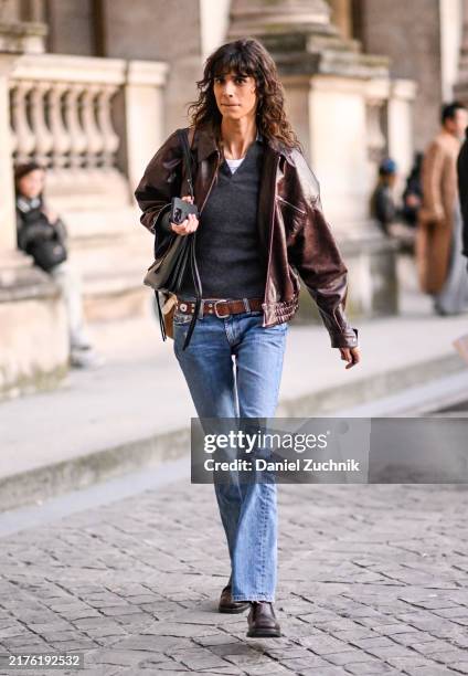 Model Mica Arganaraz is seen wearing a brown leather jacket, black sweater, blue jeans, brown belt and black bag outside the Louis Vuitton show...