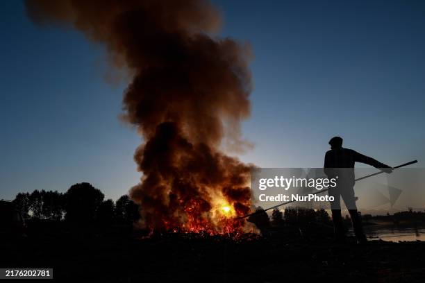 Workers set cables on fire, causing air pollution as they extract copper on the outskirts of Sopore, Jammu and Kashmir, India, on October 6, 2024.