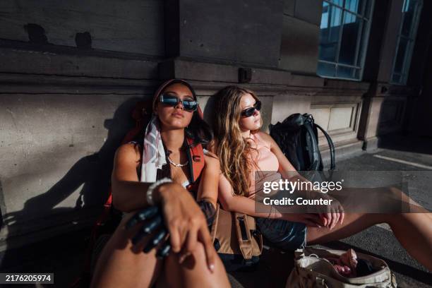 two young women sitting outside a train station. - railroad station stock pictures, royalty-free photos & images
