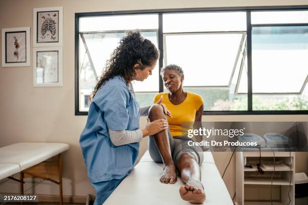 physiotherapist doing rehabilitation on elderly woman's knee - knee stock pictures, royalty-free photos & images