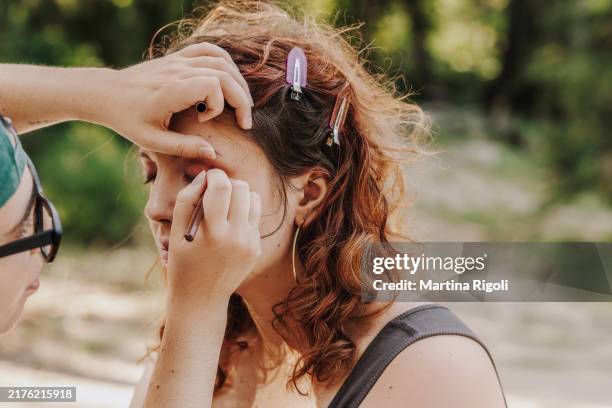 make-up artist applying eyeliner on model's eyelid - schoonheidsspecialist natuur stockfoto's en -beelden