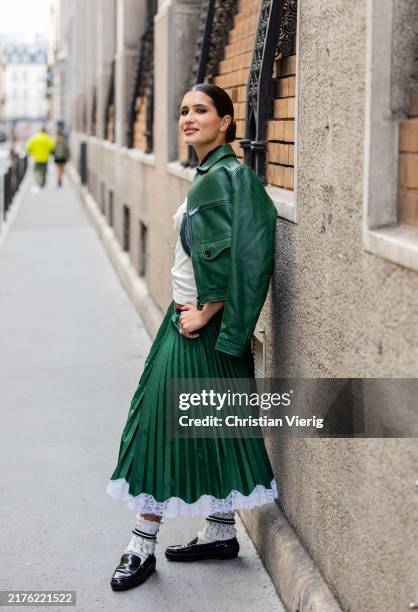 Guest wears green leather jacket, pleated skirt outside Lacoste during Womenswear Spring/Summer 2025 as part of Paris Fashion Week on October 01,...