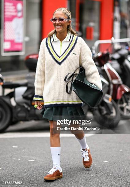 Caetana Botelho Alfonso is seen wearing Lacoste sweater, white top, black panel skirt, white Lacoste socks, brown shoes and Lacoste large bag with...