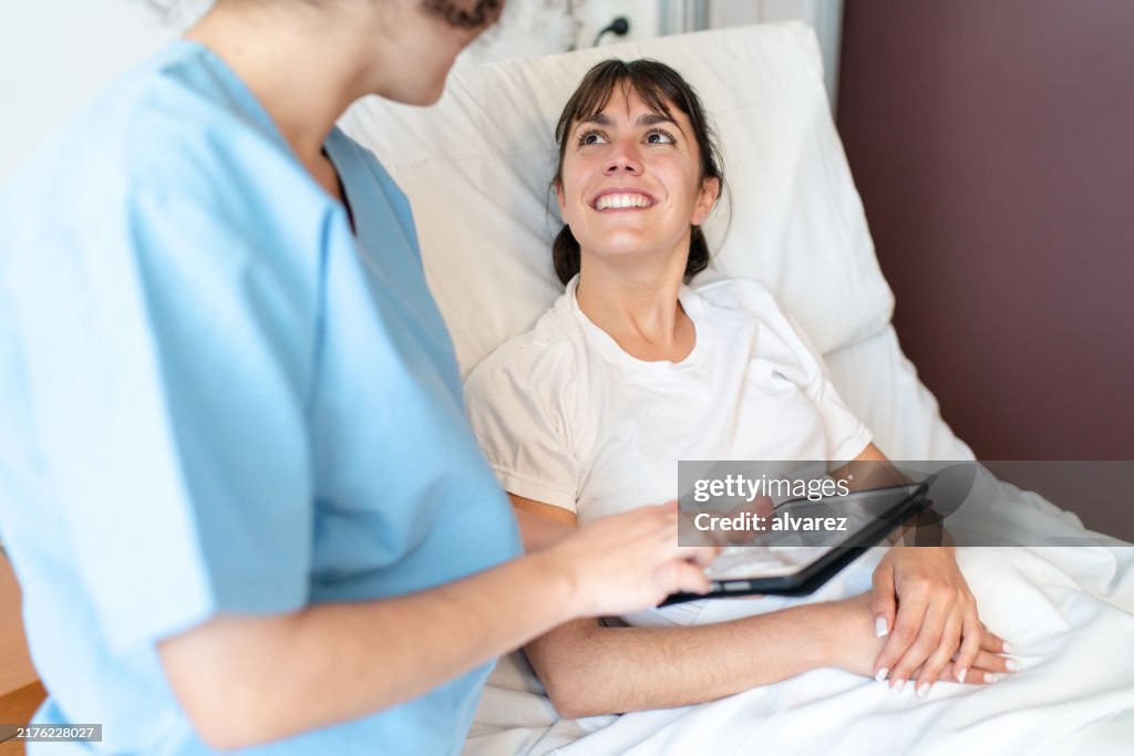 Enfermera discutiendo los resultados de las pruebas médicas en una tableta digital con una paciente