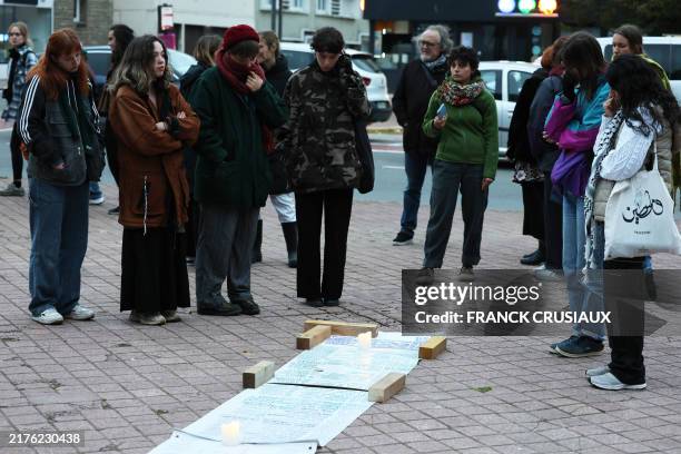 People stand around a banner with the names of migrants who died crossing the English Channel during a tribute gathering in Calais, northen France,...