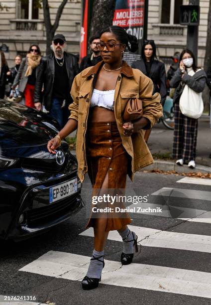 Guest is seen wearing a brown Miu Miu jacket, white bustier, brown Miu Miu skirt, beige Miu Miu bag and black shoes with gray socks outside the Miu...