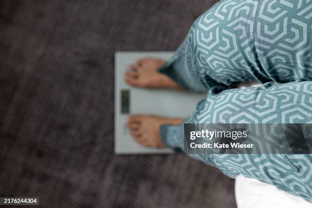 close-up of unrecognizable woman standing on weight scales. high angel view - obesitas stockfoto's en -beelden