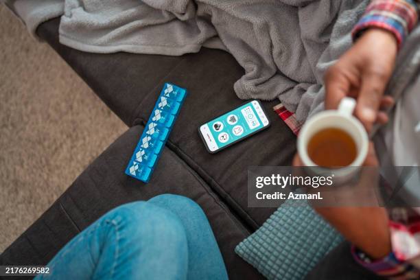 unwohle frau, die zu hause medikamente einnimmt - krankenstand stock-fotos und bilder