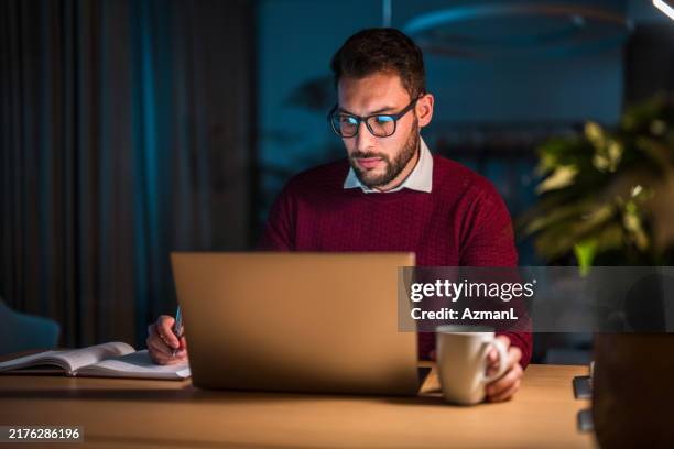 profesional masculino hispano que trabaja hasta tarde en el escritorio de la oficina - hombres-de-mediana-edad fotografías e imágenes de stock
