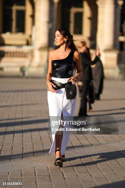Tamara Kalinic wears silver earrings, black asymmetrical sequin Louis Vuitton top, white high waisted high slit black leather belt Louis Vuitton midi...