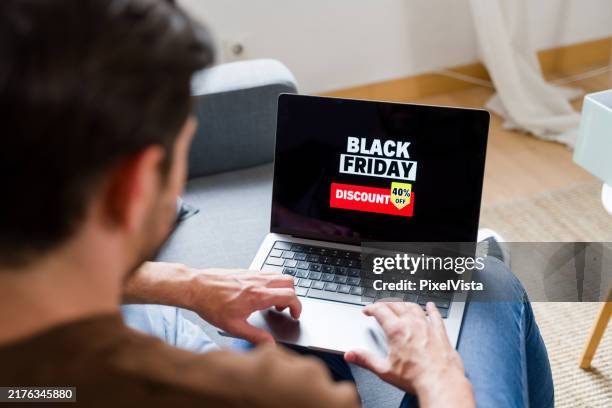 man shopping online during black friday using laptop at home - black friday bildbanksfoton och bilder