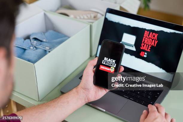 man shopping online during black friday using laptop and smartphone - black friday bildbanksfoton och bilder