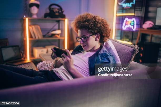 teenage boy playing mobile game at home - redhead gamer stock pictures, royalty-free photos & images