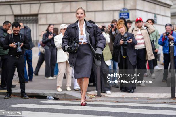 Leonie Hanne wears white Miu Miu bralette, white buttoned up long sleeve tied shirt, dark gray Miu Miu blazer jacket, black high waisted Miu Miu over...