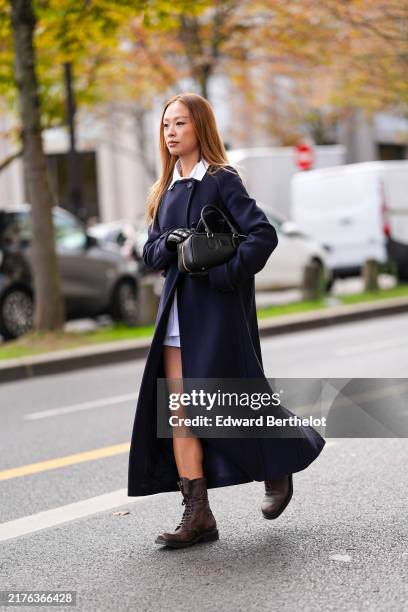 Niki Wu Jie wears white buttoned up long sleeve shirt, dark navy blue wool Miu Miu coat, shiny black leather gloves, shiny black Miu Miu leather bag,...