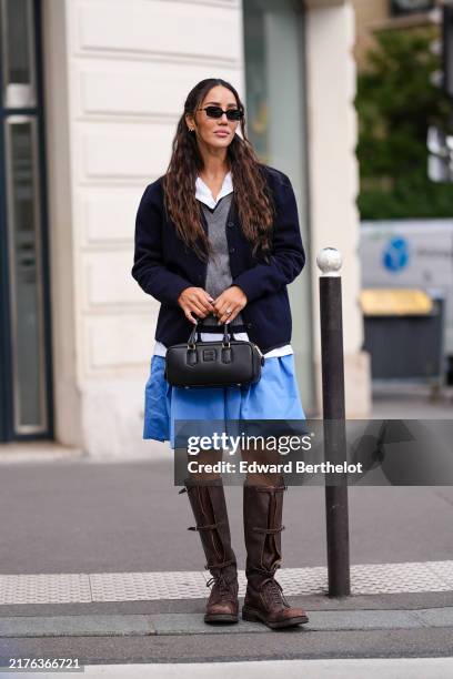 Tamara Kalinic wears black sunglasses, silver earrings, white buttoned up oversized long sleeve shirt, dark gray Miu Miu vest, navy blue Miu Miu...