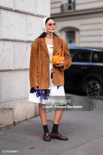 Guest wears dark brown sunglasses, white textured cap, dark brown suede oversized Miu Miu blazer jacket, cream tank top, white loose purple floral...