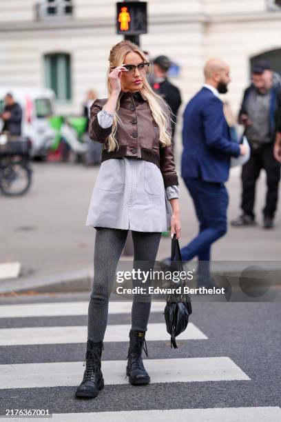 Guest wears black glasses, dark brown cropped leather bomber jacket, light gray oversized shirt dress, dark gray wool tights, shiny black Miu Miu...
