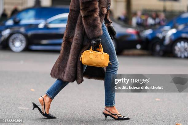 Caroline Daur wears a bright orange Miu Miu leather bag, black pointed toe strappy slingback leather Miu MIu heels, outside Miu Miu, during the Paris...