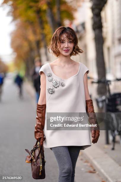 Guest wears light brown beige Miu Miu mini dress with silver embroidered detail, dark brown leather gloves, dark brown Miu Miu leather bag, bag...