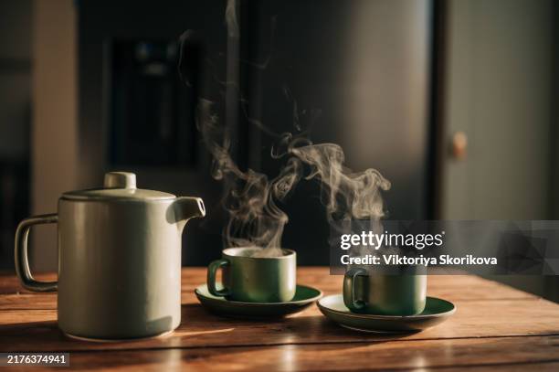 tea is poured from a green teapot into matching mugs - theepot stockfoto's en -beelden