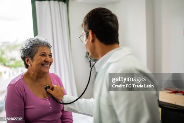 médico que escucha los latidos del corazón de una paciente mayor durante una consulta en el hospital - prevencion fotografías e imágenes de stock