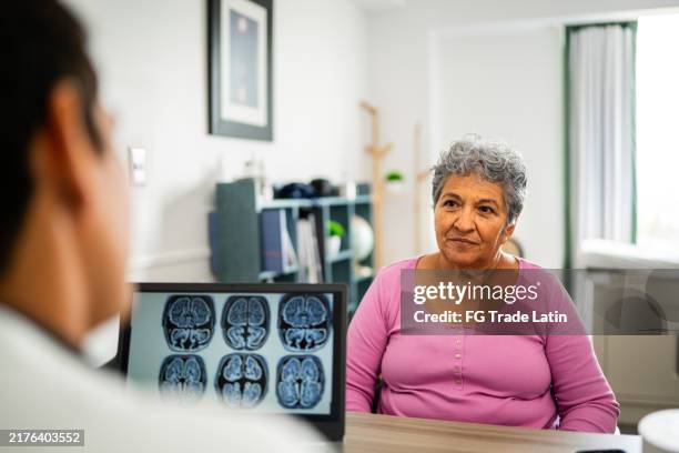 senior woman talking to doctor during consultation at hospital - neurologist stock pictures, royalty-free photos & images