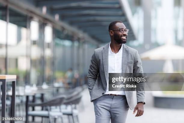 confident businessman walking outside modern office building - businessman hands in pockets stock pictures, royalty-free photos & images