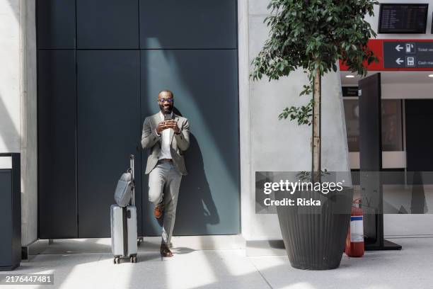 business traveler using smart phone at the public station - business travel stock pictures, royalty-free photos & images