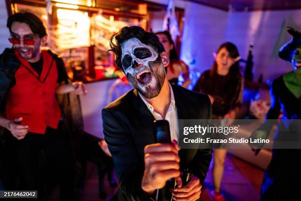 hombre adulto medio bailando y cantando karaoke con amigos en una fiesta de halloween - disfraz fotografías e imágenes de stock