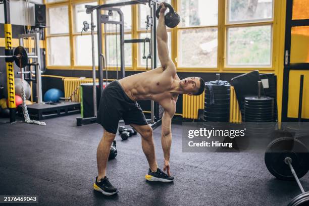 man executing kettlebell stretch in spacious gym - kettle bell stock pictures, royalty-free photos & images