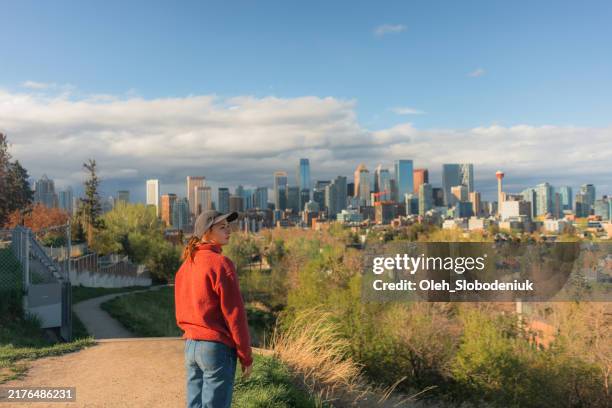 woman looking at calgary cityscape from park - calgary stock pictures, royalty-free photos & images