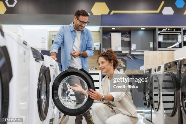 mid adult couple shopping for a new washing machine at the appliance store - household appliance stock pictures, royalty-free photos & images