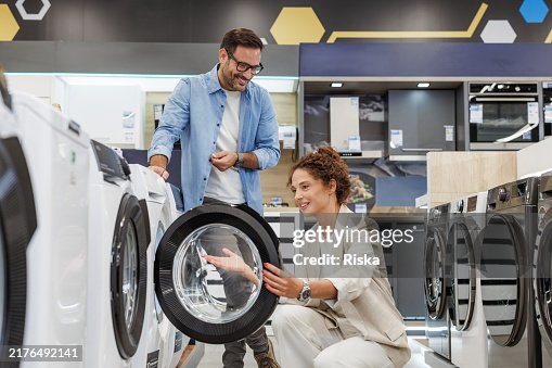 Mid adult couple shopping for a new washing machine at the appliance store Mid adult couple shopping for a new washing machine at the appliance store