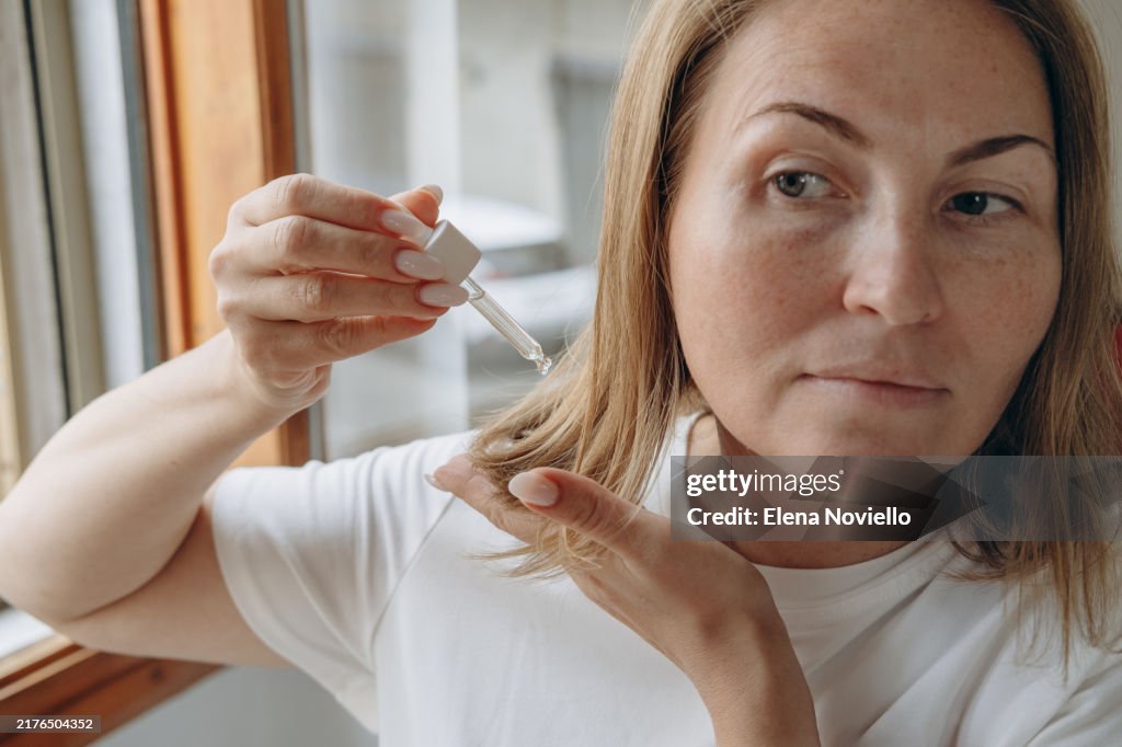 Woman drops hair growth serum or hair oil with a dropper , hair care