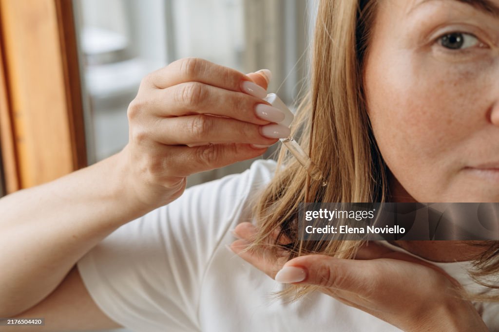 Woman drops hair growth serum or hair oil with a dropper , hair care