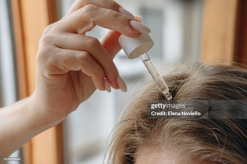 Woman drops hair growth serum or hair oil with a dropper , hair care