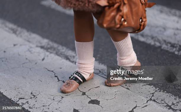Fashion Week guest is seen wearing a long fluffy rose vest, a rectangular brown leather bag with silver details, pale pink legwarmers, and beige...