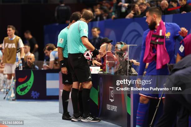 Referees check the video support monitor during the FIFA Futsal World Cup Uzbekistan 2024 semi-final match between France and Argentina at Humo Arena...