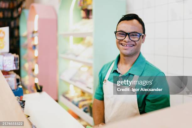 young man with down syndrome working at the checkout counter - neurologische aandoening stockfoto's en -beelden