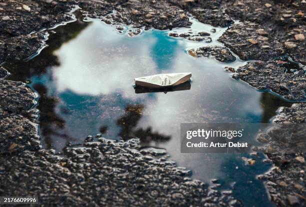paper boat reflections hope and imagination in urban stillness - surrealismo fotografías e imágenes de stock
