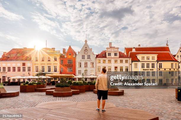 rear view of a man standing at town hall square in tallinn old town, estonia - tallinn stock pictures, royalty-free photos & images