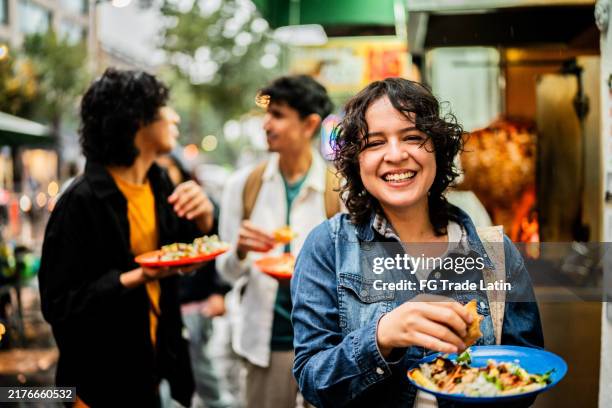 portrait of young woman eating taco in mexico city - eating taco portrait stock pictures, royalty-free photos & images