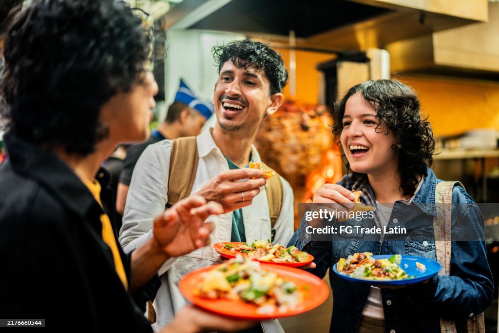 Young friends talking and eating taco outdoors