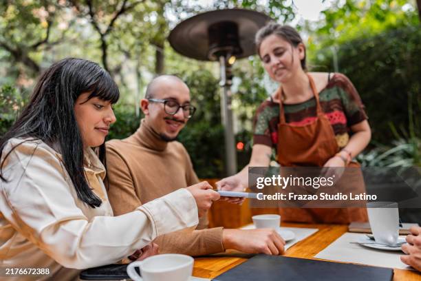 jeune femme effectuant un paiement sans contact dans un café - paiement sans contact photos et images de collection