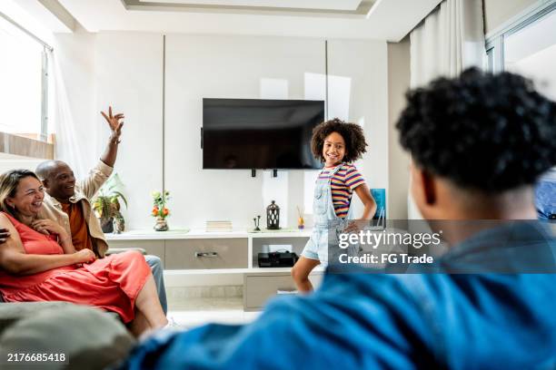 girl playing charades with her family at home - pantomime stock pictures, royalty-free photos & images