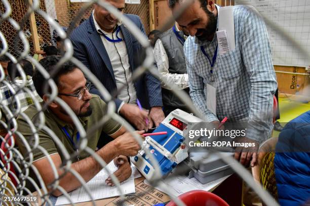 Electoral officials tally votes from an Electronic Voting Machine at a polling counting centre in Srinagar. Counting of votes began for 90 Assembly...